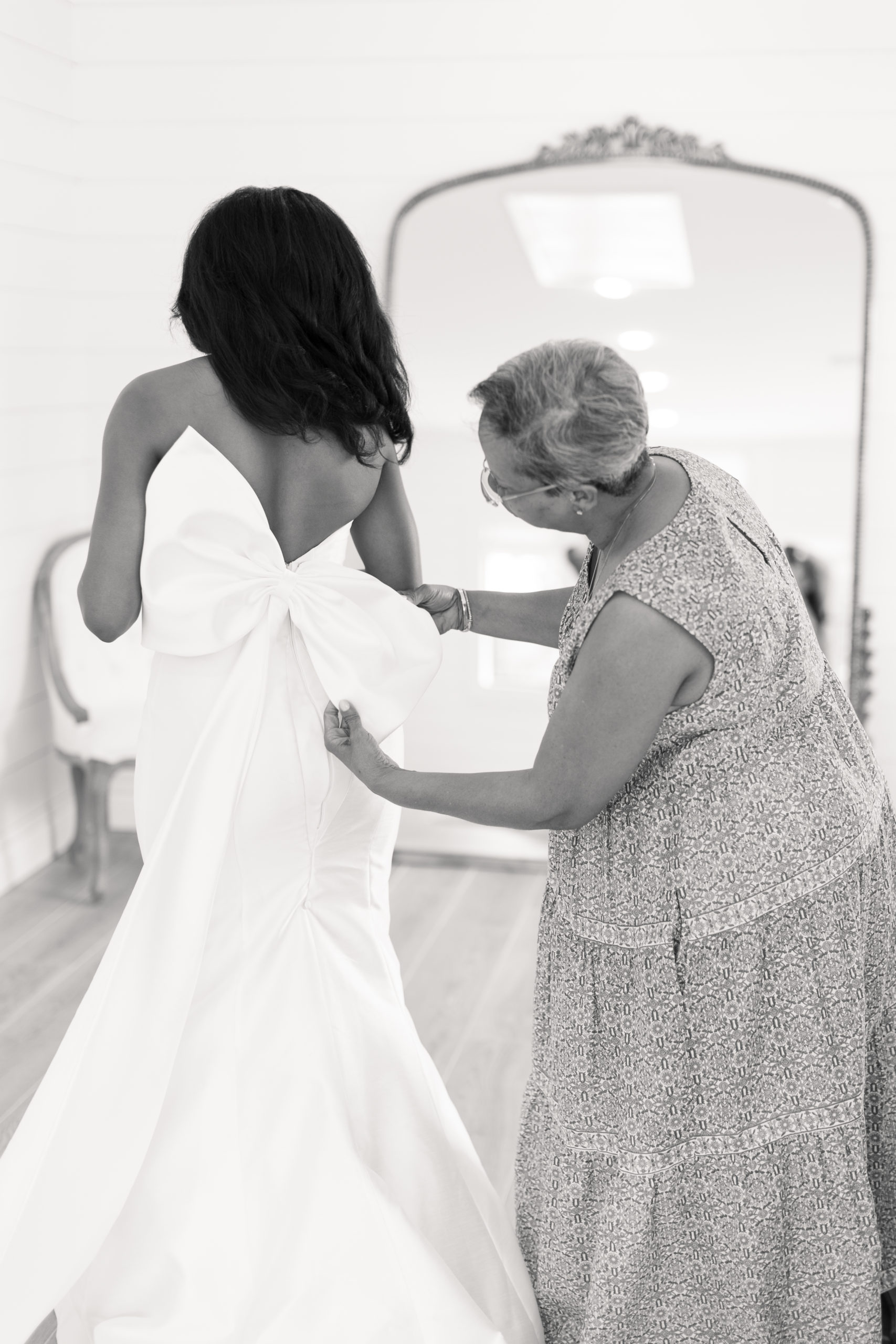 Styl'd Grace Blogger Brittainy Lemelle shares her bridal portraits - black and white photo of a bride with a woman helping her with her wedding dress